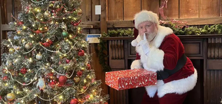 An old man wearing Santa Claus dress putting a gift